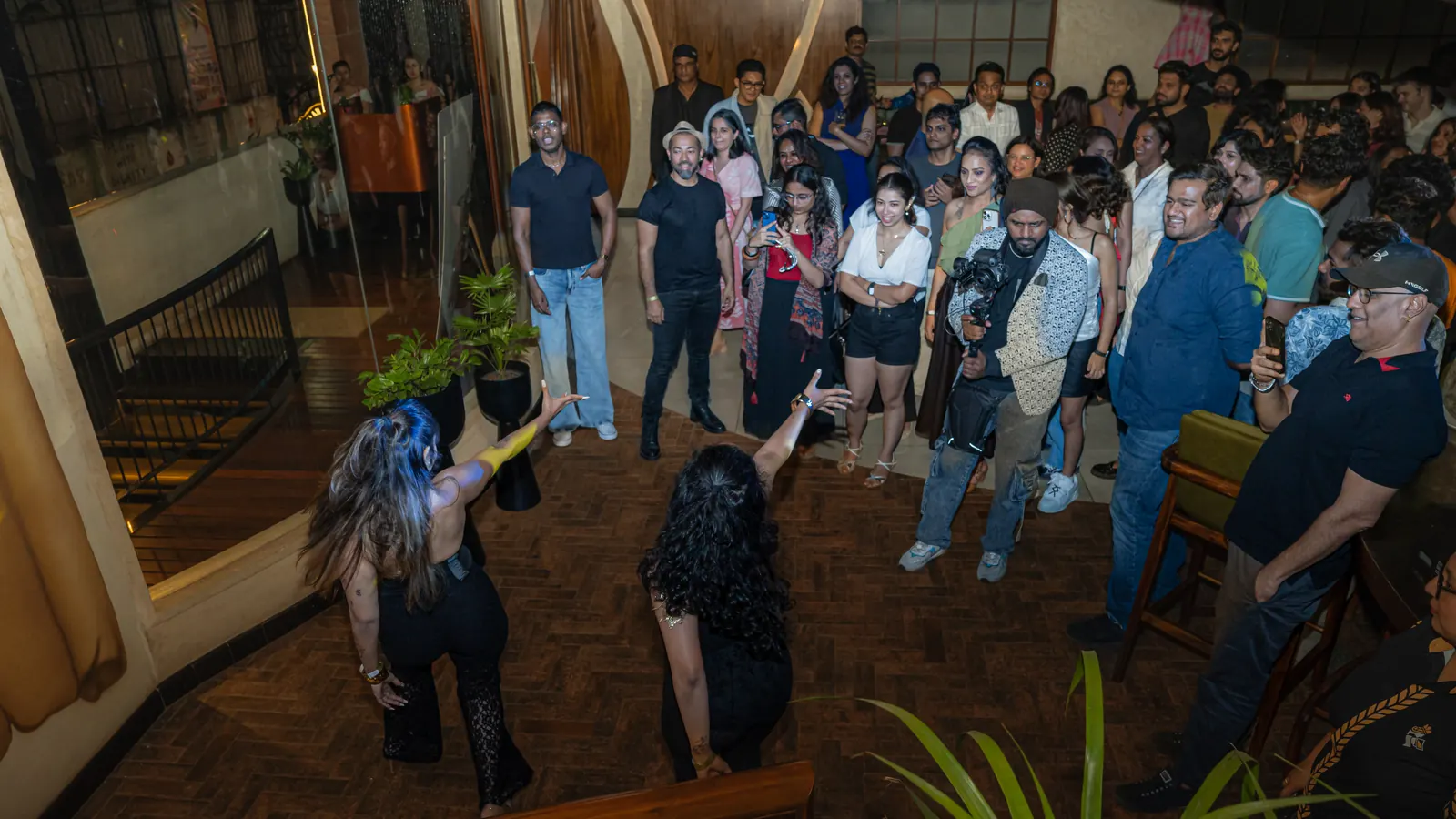 The crowd circles two dancers on the wood floor